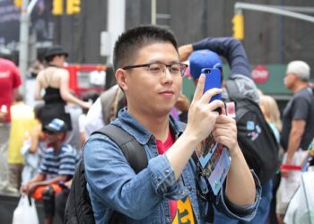 Un turista asiático tomando una fotografía con su iPhone en una foto de archivo.