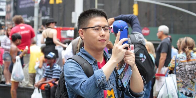 Un turista asiático tomando una fotografía con su iPhone en una foto de archivo.