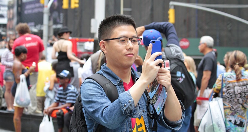Un turista asiático tomando una fotografía con su iPhone en una foto de archivo.