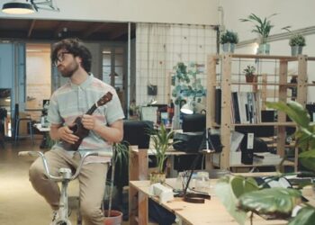 Creativo encomendándose al "big thinking" sobre una bicicleta estática y tocando un ukelele