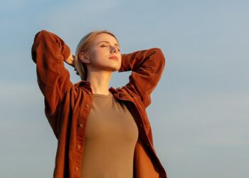 Blonde woman in shirt in sunset time on with sky on background